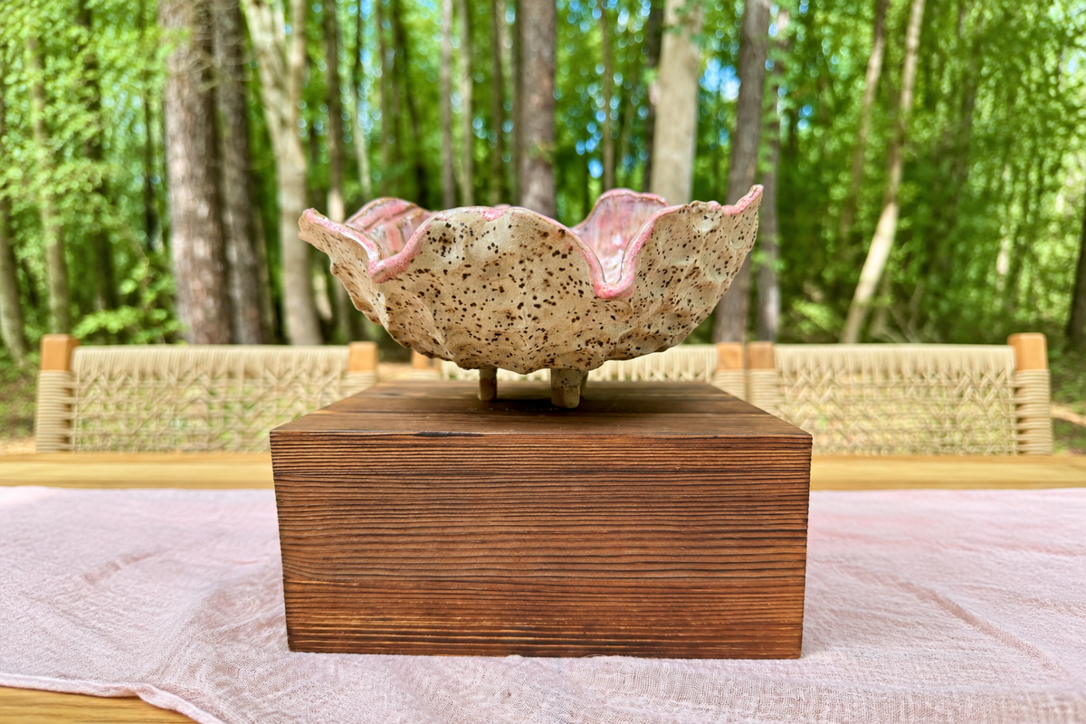 Garden Blossom Serving Bowl with pink-edged ceramic petals and earthy speckles, shown in a wide woodland setting.